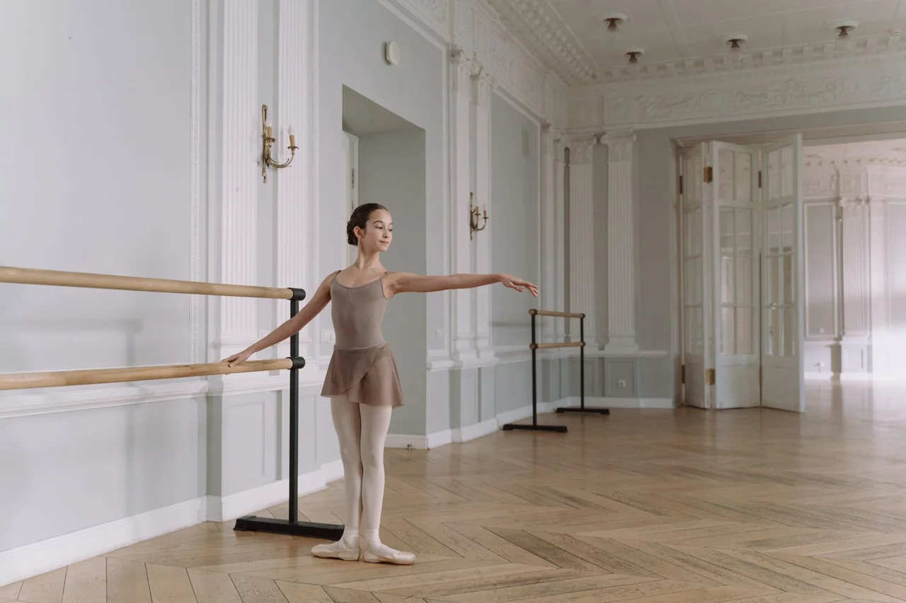 Smooth dual-height wooden ballet barres mounted along studio wall mirrors