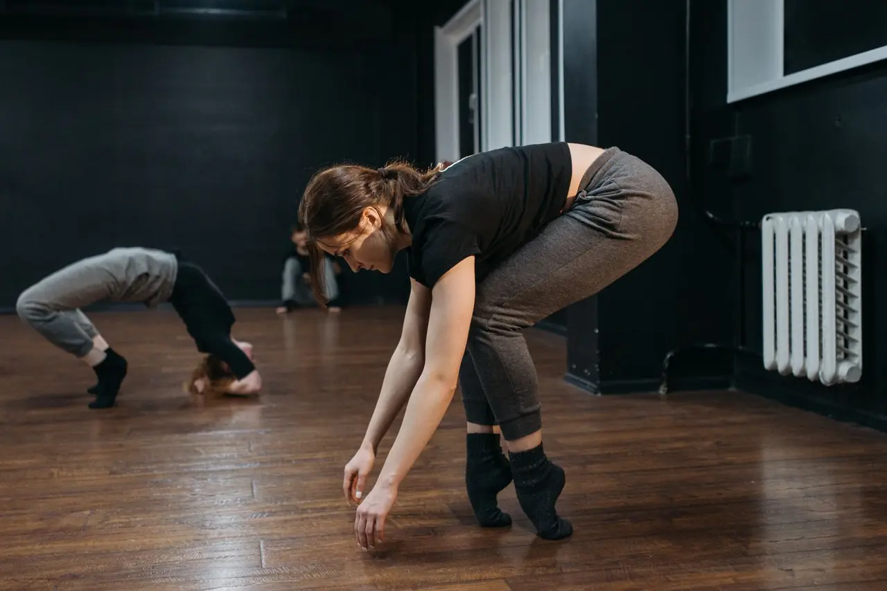 Dancers practicing expressive contemporary movement on wooden studio floor