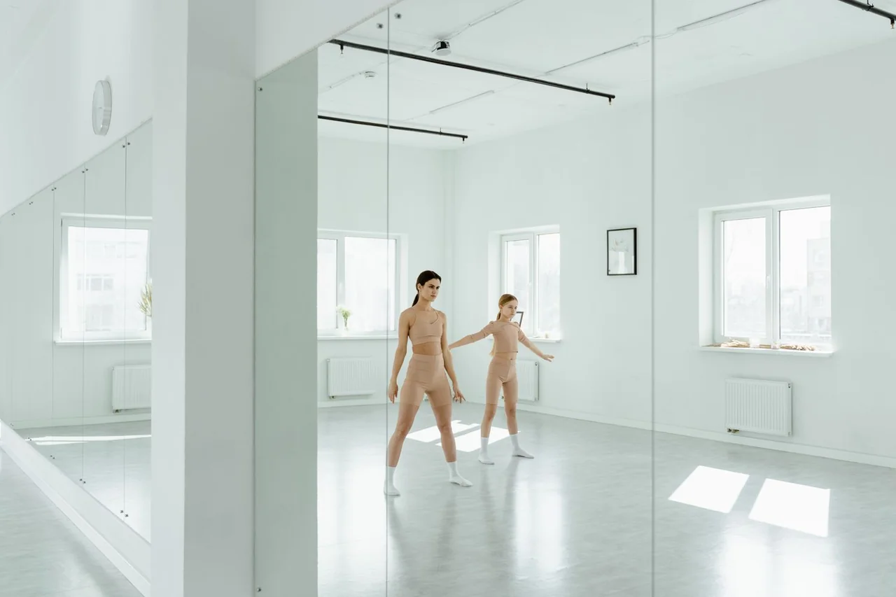 Dancers collaborating in a bright rehearsal studio with mirrored reflections