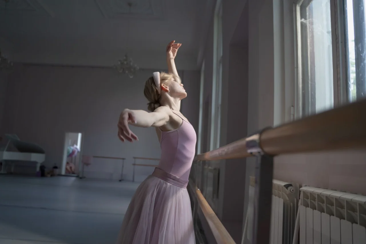 Ballet dancer practicing with poise and line in a natural light dance studio