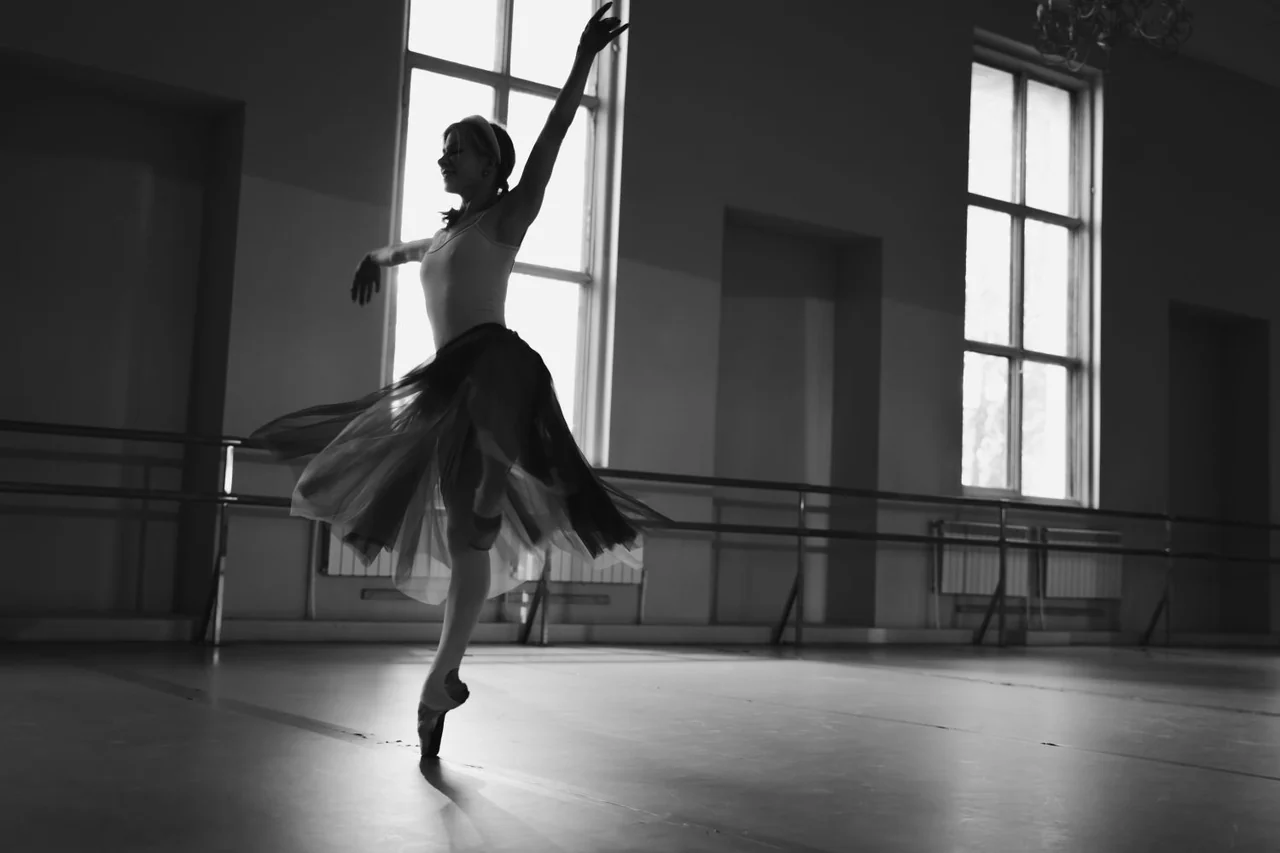 Poised dancer practicing expressive lines in a light-filled studio